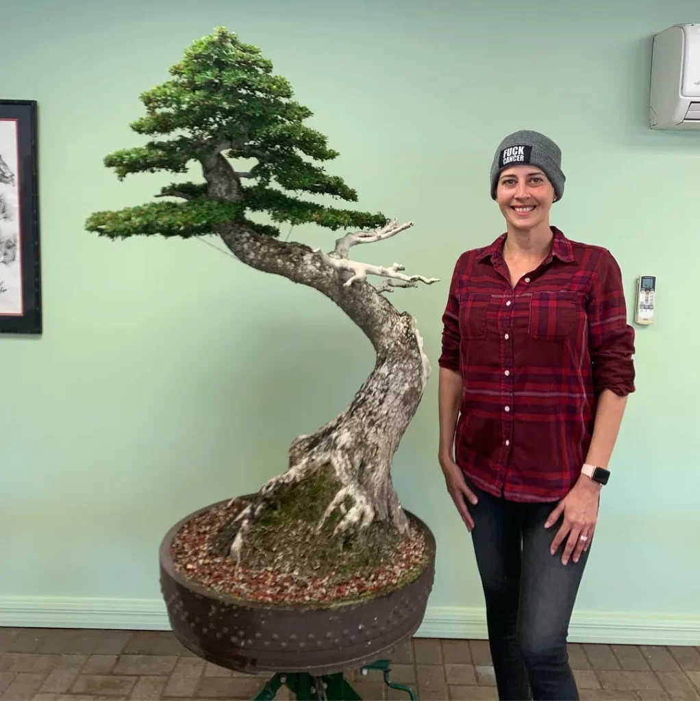 Happy Girl Posing with Black Olive Bonsai (Bucida Spinosa) Tree Displayed on Metal Stand at Home