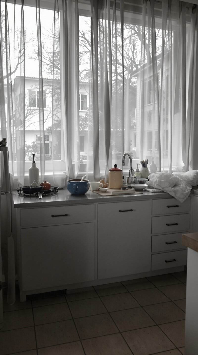 A kitchen with sheer curtains allowing natural light to enter, creating a bright and airy atmosphere.
